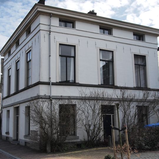 Blokvormig pand, gepleisterd met verdieping en mezzanino onder flauwhellend, met pannen gedekt schilddak