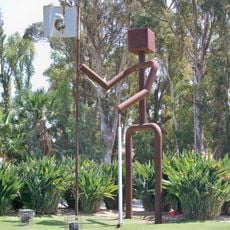 Escultura que representa de forma esquemática la figura de un golfista sosteniendo el banderín de un hoyo.