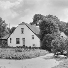 Gepleisterde boerderij onder rieten wolfdak. Het woongedeelte heeft rechts een opkamer