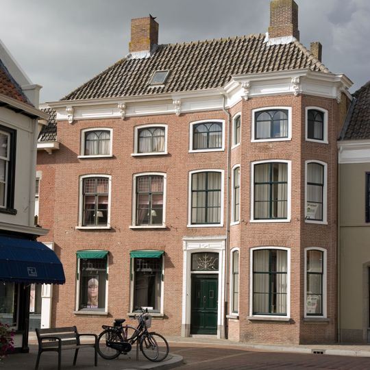 Monumentaal herenhuis met driezijdige uitbouw, segmentvormig overtoogde vensters met Empire roedenverdeling, kroonlijst op consoles