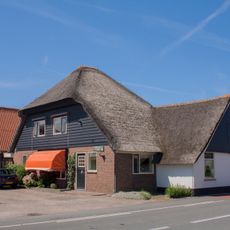 Met riet gedekte stolp met woonhuis en achterhuis, beiden houten top. De grootste top met snijwerk langs de bebording