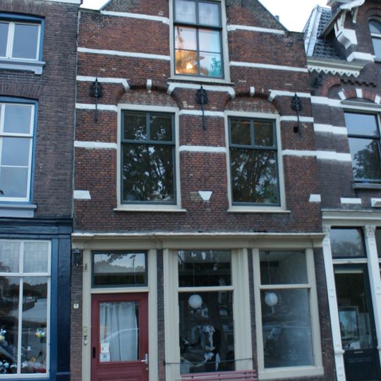 Pand met oorspronkelijk trapgevel met in de verdieping korfbogige ontlastingsbogen, waarin vlechtwerk