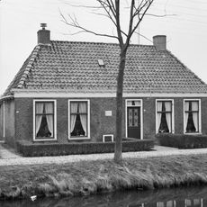 Dubbel landelijk pand met stichtingssteen en goot op klossen onder schilddak met twee hoekschoorstenen (vormt een geheel met nr. 28)