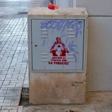 Grafiti de plantilla con una imagen de la Virgen María junto al texto «¡¡Recoge la caquita, por la Virgen!!».