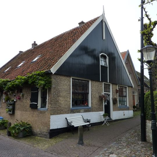 Fors gaaf hoekpand met houten voorschot waarin luik; vensters met roedenverdeling