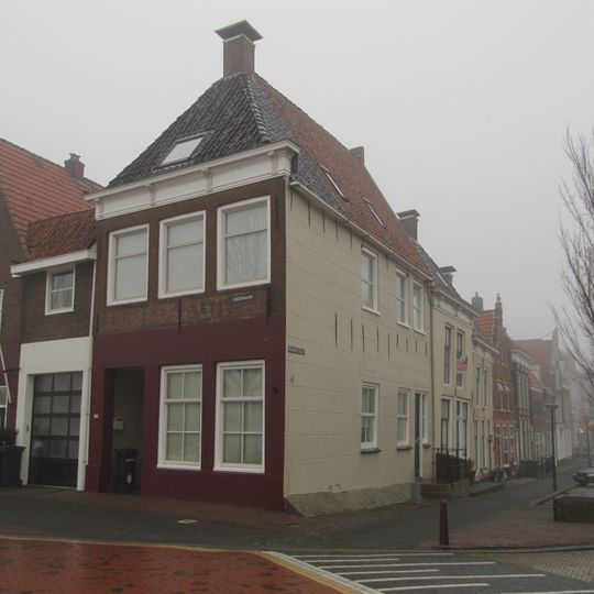 Hoekpand onder zadeldak tegen achtertop en voorgevel met kroonlijst en voorschild met topschoorsteen