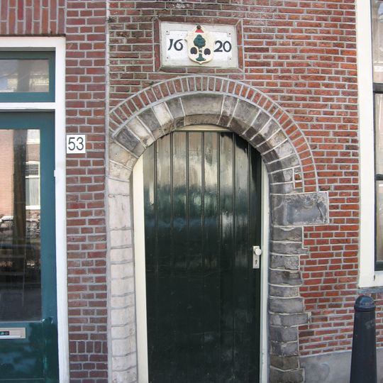 Een getoogd natuurstenen poortje, waarboven gevelsteen met voorstelling van een boom en jaartal