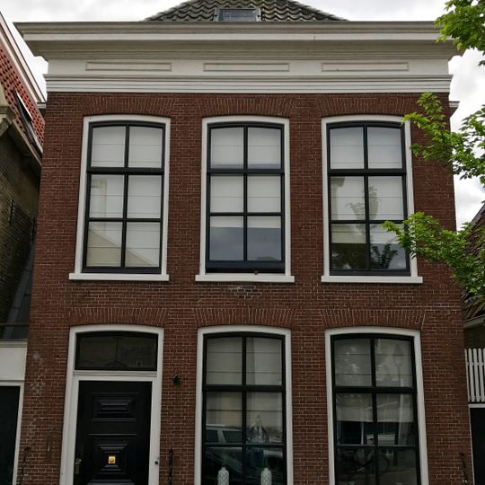 Pand met verdieping en rechte kroonlijst onder schilddak met twee topschoorstenen gedekt met borden