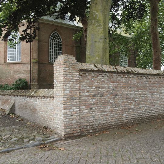 Bakstenen muur van wisselende hoogte om kerkhof