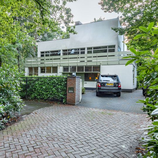 In baksteen opgetrokken, witgepleisterd, vrijstaande, vlak gedekt woonhuis