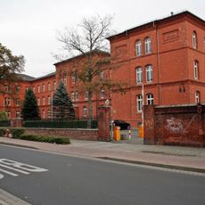 Schule, mit Einfriedung, Grünfläche vor der Schule (mit Wegpflasterung) und Turnhalle im Schulhof Dübener Straße 20