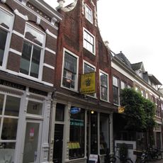 Pand met klokgevel met vooruitspringend middenstuk, versierd met guirlandes van natuursteen, ter weerszijden vazen, halfrond fronton bekroont de gevel, begin 18e eeuw verbouwd