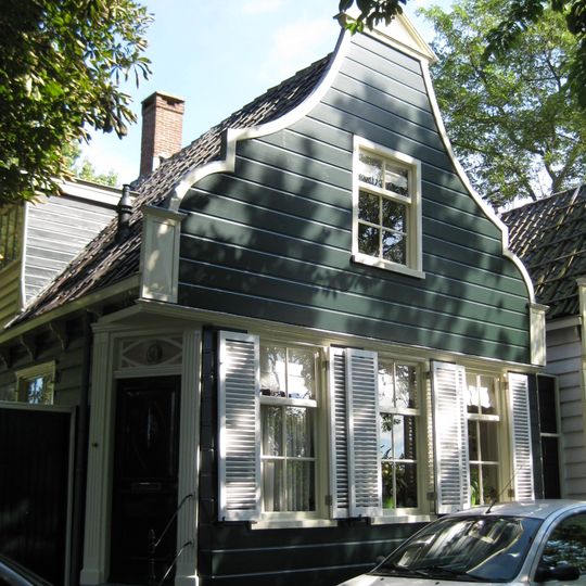 Houten dijkhuis met klokgevel uit 19de eeuw, overhoekse plaatsing voordeur