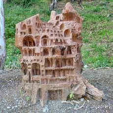 Tocón de eucalipto tallado a modo de escultura simulando un edificio o ciudad medieval abigarrada.