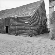 Houten schuur met mooi, hoog pannen dak en stenen noordgevel. Onder een dak met het buurnummer 1
