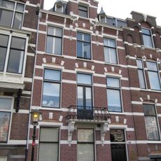 Pand in neo-renaissance trant met trapgevel boven de middenas. De gevel is versierd met geblokte ontlastingsbogen en banden