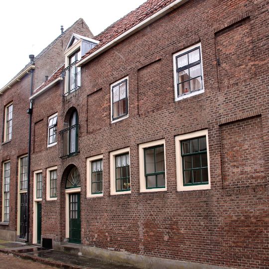 Achter de Waag een pakhuis met verdieping en schilddak, waarop aan de zuidzijde een windwijzer. Getoogde poort, waarboven getoogd hijsvenster en dakvenster met fronton en hijsbalk