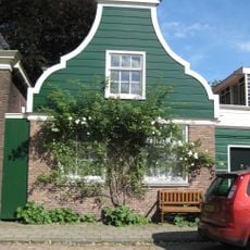 Houten dijkhuis met klokgevel (uit- en ingezwenkt voorschot), bakstenen onderpui