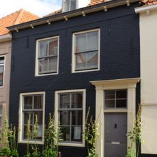 Pand met lijstgevel van midden 19e-eeuws karakter. Deuromlijsting met gecanneleerde pilasters en hoofdgestel. Schilddak