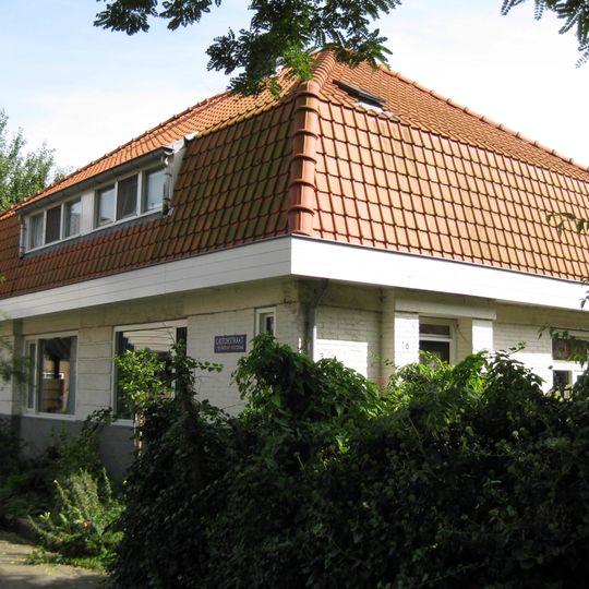 Woning met stijlelementen in de Amsterdamse School, gebouwd met voor die tijd nieuw systeem met betonblokken