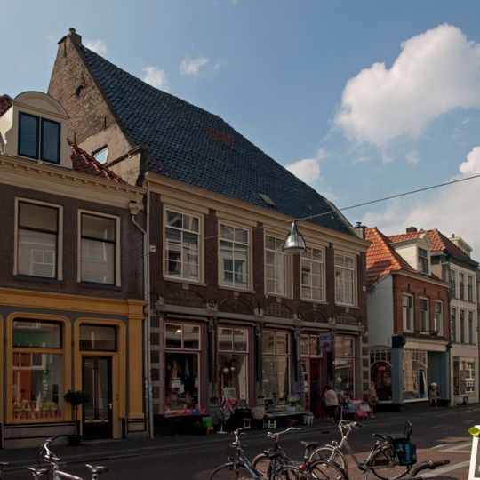 Hoekpand met jongere pui in de voorgevel en waterlijsten en fragmenten van dichtgemetselde zandstenen kozijnen in de zijgevel