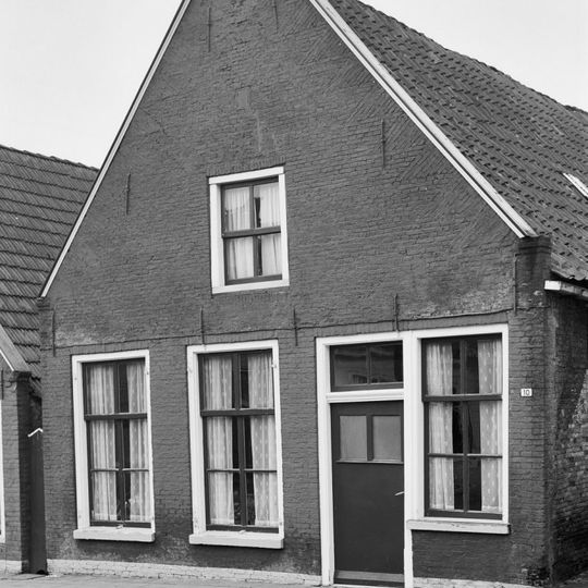 Pand tegen topgevel met deklijsten en zes- en vierruitsvensters onder zadeldak met topschoorsteen