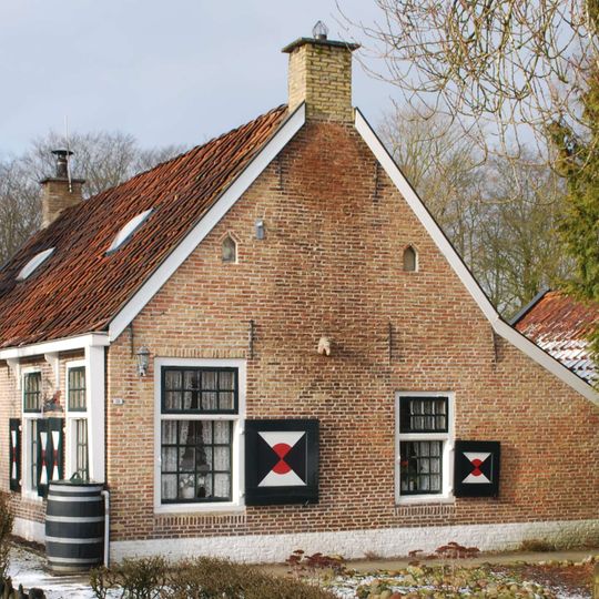 Eenvoudige zogenaamde eksteurswoning met vensters met roeden onder dwars dak tussen topgevels met topschoorsteen