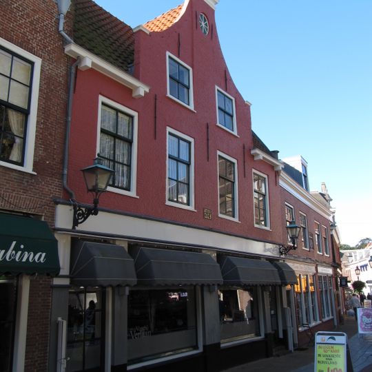 Pand met fraaie gevel met in midden hoog oprijzende topgevel, zadeldak eveneens in topgevels eindigend