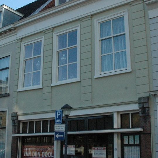 Pand met gepleisterde lijstgevel van midden 19e-eeuws karakter. Eenvoudige stoeppalen